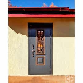 Входная дверь выполнена под заказ с отделкой ковкой и стеклопакетом